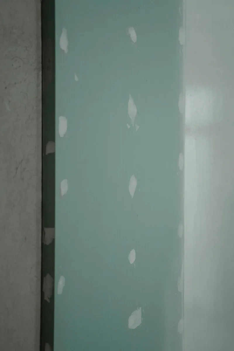 A tired interior wall with scuffs, patched drywall, and yellowed trim.